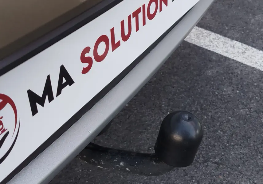 Gros plan sur l'attelage arrière noir d'une Dacia Sandero Stepway beige dune, avec plaque d'immatriculation partielle visible.