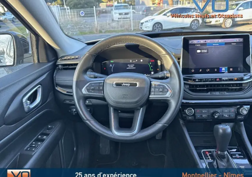 Vue intérieure centrée sur le volant cuir Jeep Compass blanc 2023 avec écran tactile et commandes au volant