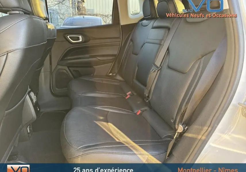 Vue intérieure des sièges arrière en cuir noir du Jeep Compass blanc 2023, avec ceinture de sécurité et porte côté droit visible.