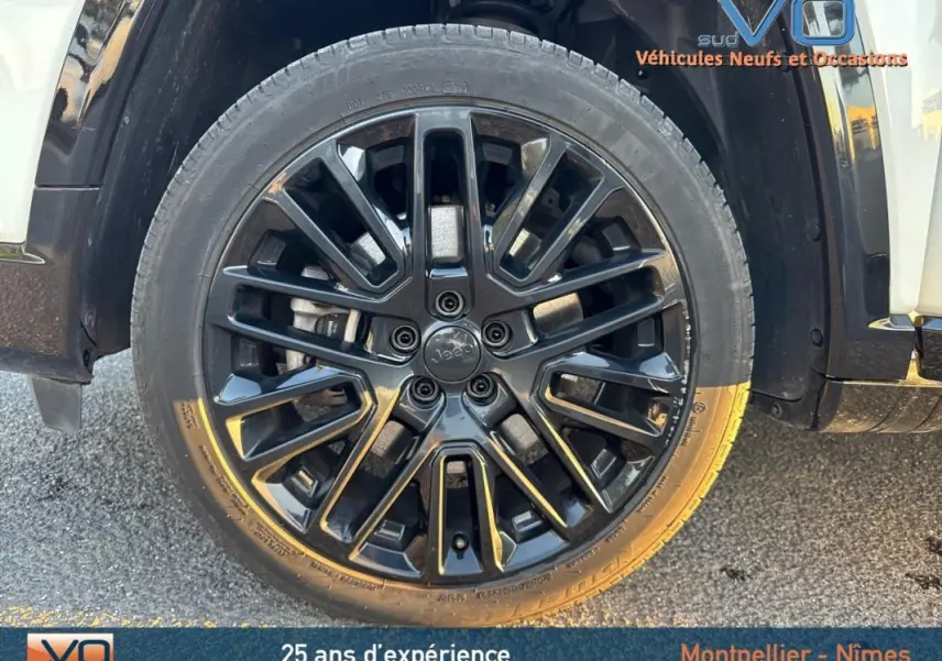 Gros plan sur la jante alliage noire de 19 pouces du Jeep Compass blanc, mettant en valeur le logo central Jeep.