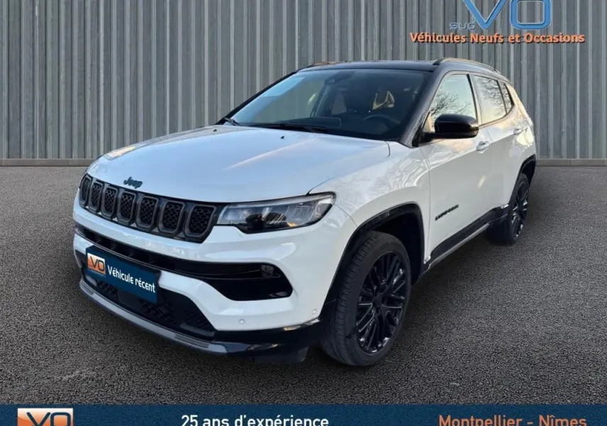 Jeep Compass blanc en 3/4 avant droit avec jantes alliage noires et barres de toit visibles.