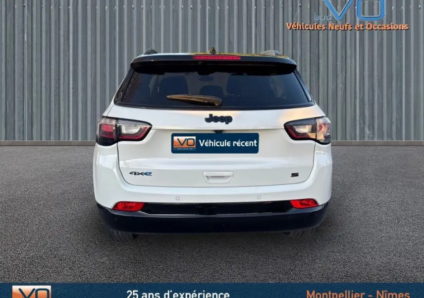 Vue arrière d'un Jeep Compass blanc 2023 avec logo 4xe et finition S, sur fond industriel gris.