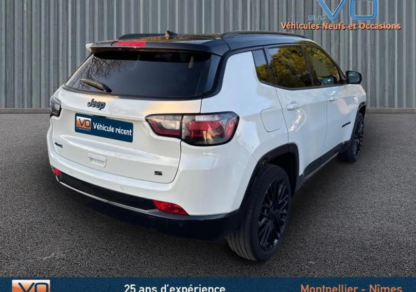 Vue 3/4 arrière droite d'un Jeep Compass blanc 2023 avec toit noir et jantes alliage noires de 19 pouces.