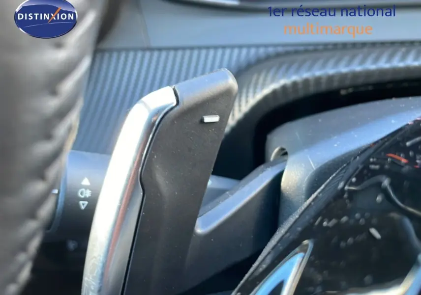 Gros plan sur la palette de changement de vitesse côté droit du volant d’une Peugeot 208 noire hybride 2025.