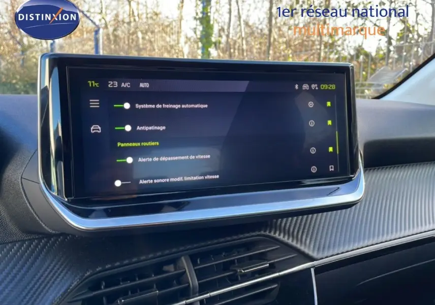 Écran tactile central affichant les aides à la conduite dans l’habitacle d’une Peugeot 208 noire, vue de face.