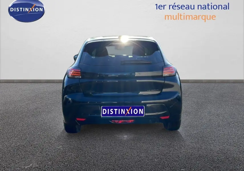 Vue arrière d'une Peugeot 208 noire 1.2 Hybrid 110ch e-DCS6 Allure, stationnée sur sol gris devant un mur blanc.