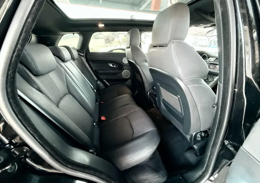 Vue intérieure côté gauche montrant les sièges arrière noirs en cuir et le toit ouvrant du Range Rover Evoque 2017.