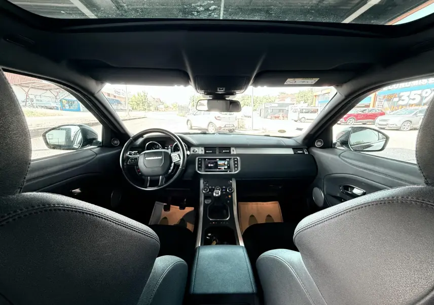 Vue intérieure avant du Range Rover Evoque noir de 2017, montrant le tableau de bord, volant et console centrale.