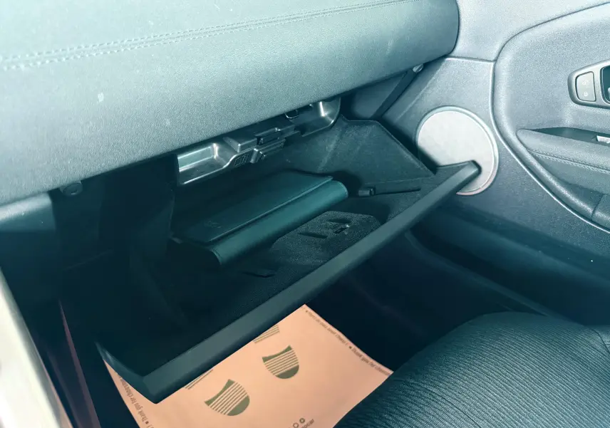 Gant de rangement ouvert côté passager avec livret noir à l'intérieur dans un Range Rover Evoque noir.