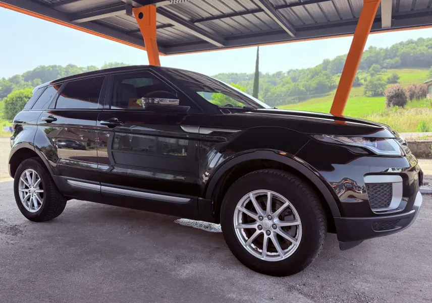 Range Rover Evoque noir vu de profil côté gauche sous un abri avec jantes argentées et vitres teintées.