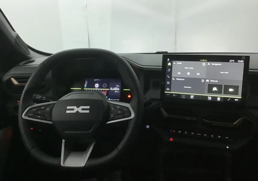 Vue intérieure du tableau de bord du Dacia Duster 2025 avec volant multifonction et écran tactile central allumé.