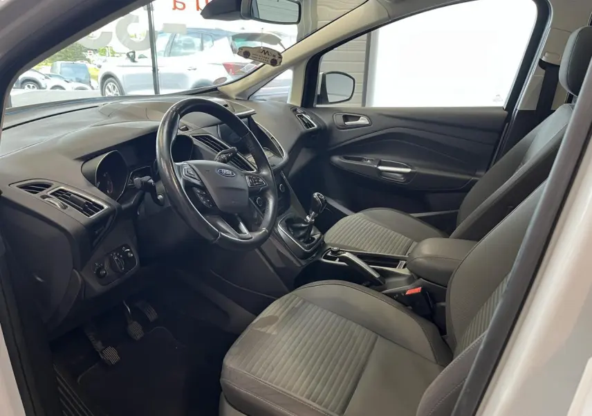 Intérieur avant gris d'une Ford C-MAX blanche 2018, vue côté conducteur avec volant cuir et boîte manuelle.