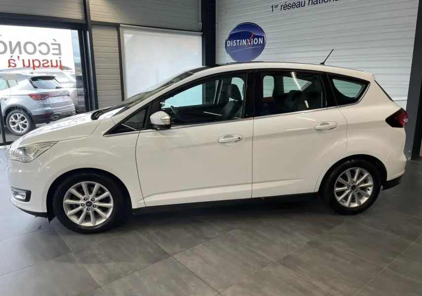 Ford C-MAX blanc vu de profil côté gauche dans un showroom avec jantes alliage et toit panoramique.