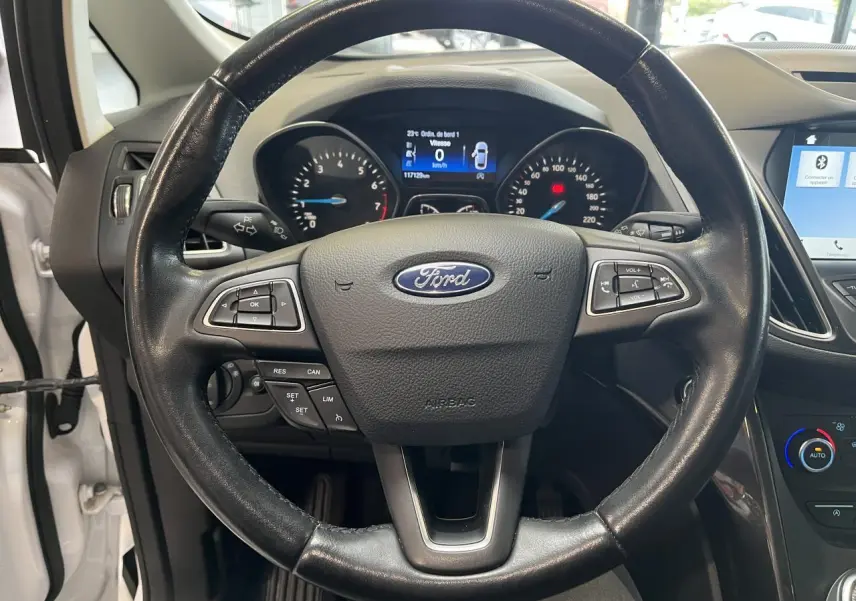 Vue rapprochée du volant en cuir noir avec logo Ford, tableau de bord et écran tactile du Ford C-MAX blanc 2018.