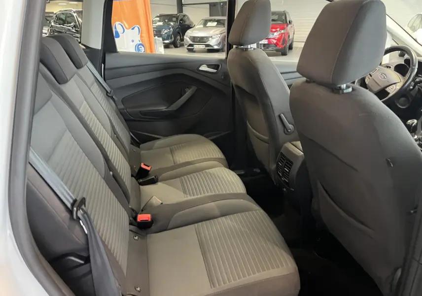 Vue intérieure côté droit des sièges arrière gris foncé du Ford C-MAX blanc, avec appuie-têtes et ceintures visibles.