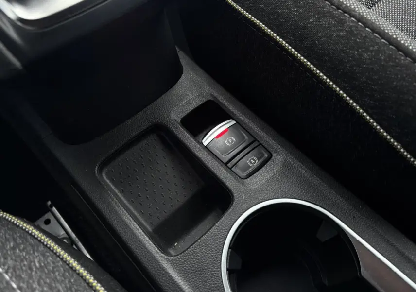 Gros plan sur la console centrale noire du Renault Captur 2025, avec frein à main électrique et accoudoir tissu.