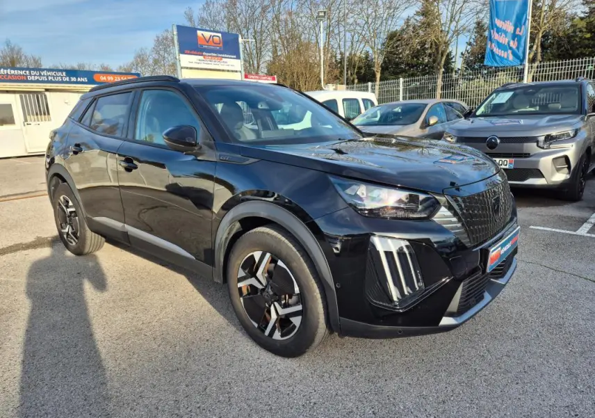 Peugeot 2008 Hybrid 145 e-DCS6 GT noir en 3/4 avant droit avec barres de toit et jantes alliage 18 pouces.