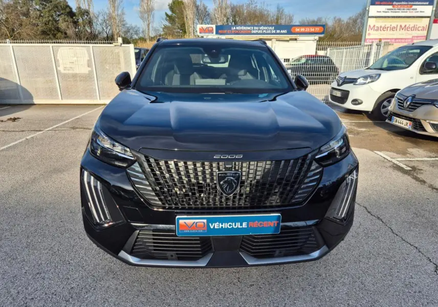Vue frontale d’un Peugeot 2008 Hybrid 145 e-DCS6 GT noir avec calandre distinctive et feux LED verticaux allumés.