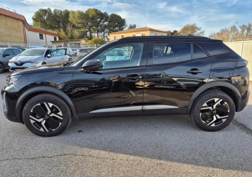Vue latérale droite du Peugeot 2008 Hybrid 145 e-DCS6 GT noir avec jantes alliage 18 pouces et barres de toit.