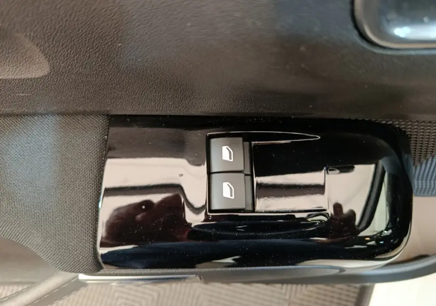 Gros plan sur les commandes de lève-vitres avant gauche d'une Citroën C3 blanche, finition intérieure noire brillante.