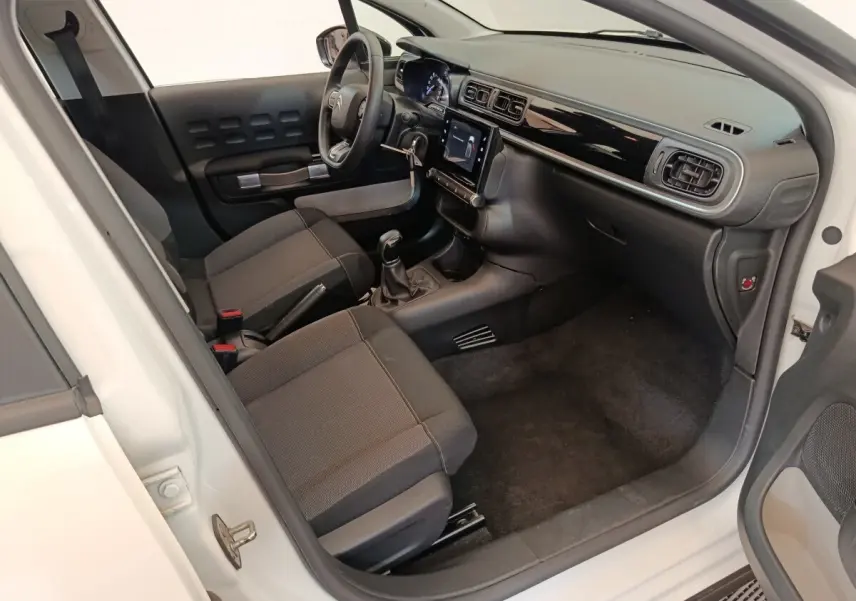 Vue intérieure côté conducteur de la Citroën C3 blanche 2020 avec tableau de bord noir et écran tactile central.