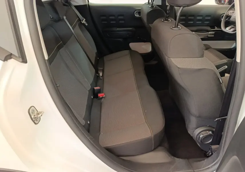 Vue intérieure arrière côté gauche d'une Citroën C3 blanche 2020 avec banquette noire et détails de porte assortis.