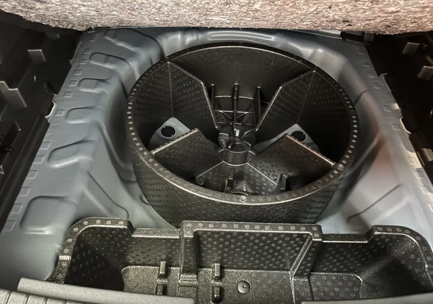 Coffre ouvert montrant le rangement sous plancher avec compartiment rond pour roue de secours du Dacia Bigster 2026.