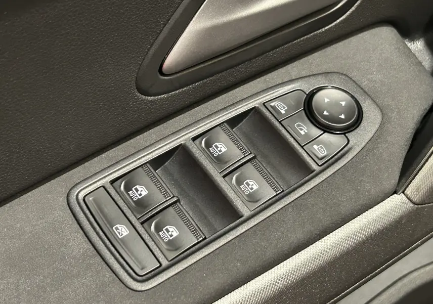 Gros plan sur les commandes de lève-vitres et réglage des rétroviseurs côté conducteur du Dacia Bigster 2026, intérieur noir.
