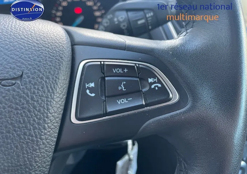 Gros plan sur les commandes audio au volant en cuir noir d'une Ford Focus SW gris magnetic de 2018.