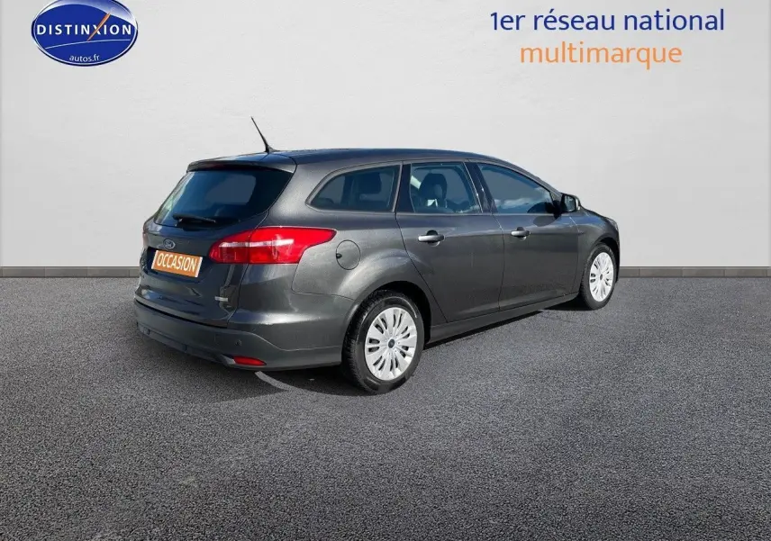 Ford Focus SW gris magnetic metal vue 3/4 arrière droit, break 5 portes en extérieur sur sol bitumé.