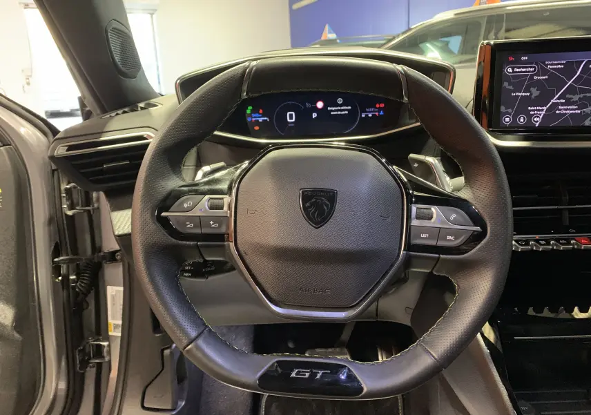 Vue rapprochée du volant cuir noir GT et du tableau de bord numérique du Peugeot 2008 gris 2023.