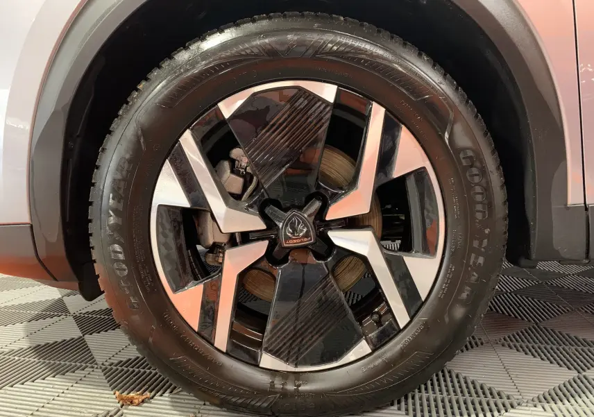 Gros plan sur la jante noire et argentée du côté gauche d'un Peugeot 2008 gris 2023 avec logo central distinctif.