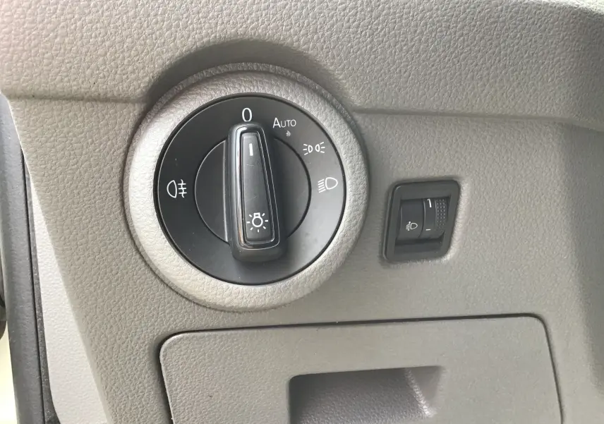 Gros plan sur le bouton de commande des phares du Volkswagen Transporter 6.1, intérieur gris clair.