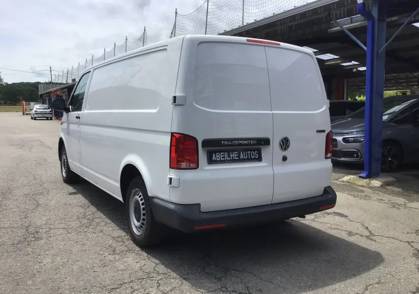 Vue 3/4 arrière droite d'un Volkswagen Transporter 6.1 blanc, fourgon utilitaire avec porte arrière pleine et pare-chocs noir.