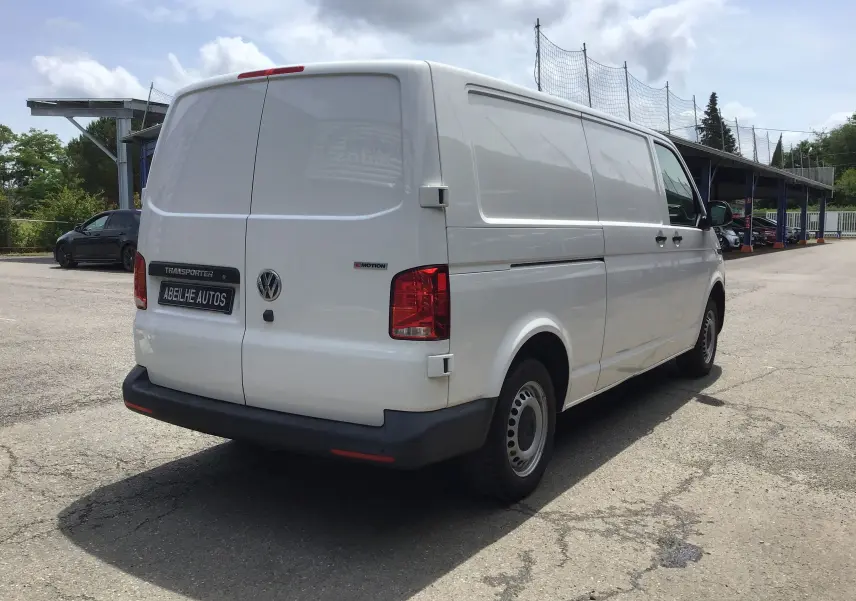 Vue 3/4 arrière droite d’un Volkswagen Transporter 6.1 blanc, fourgon utilitaire avec logo 4MOTION et plaque Abeilhe Autos.