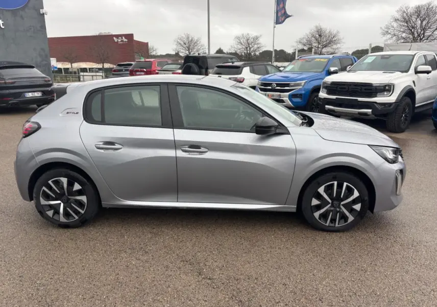 Vue de profil côté gauche d'une Peugeot 208 Hybrid 100 e-DCS6 Style gris 2025 avec jantes 16 pouces et logo Style à l'arrière.