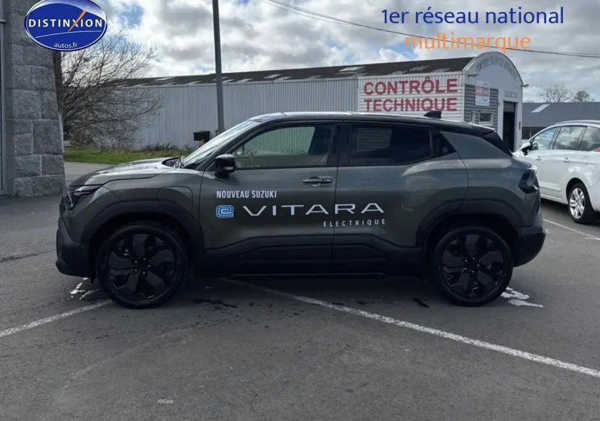 Profil gauche du Suzuki Vitara électrique 2026 en vert Land Breeze avec toit noir et jantes noires.