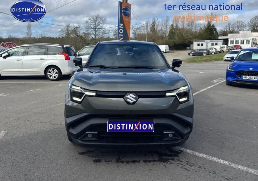 Vue de face du Suzuki Vitara 2026 gris foncé avec toit noir, sur parking extérieur sous ciel nuageux.