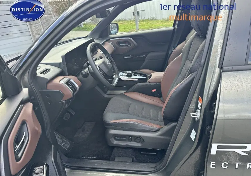 Vue intérieure côté conducteur du Suzuki Vitara 2026 vert Land Breeze avec sellerie tissu/cuir marron et noir.