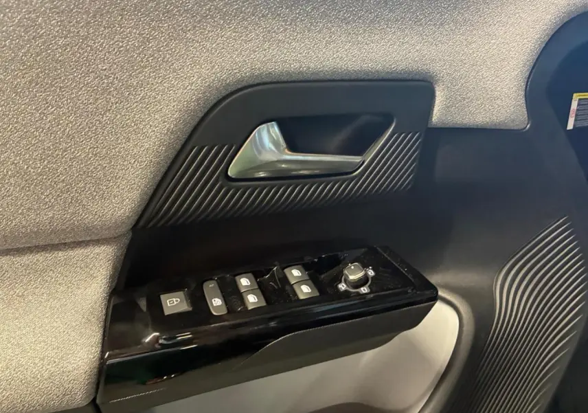 Gros plan sur la poignée de porte côté gauche du Citroën C5 Aircross 2026 vert, avec commandes de vitres et rétroviseurs.