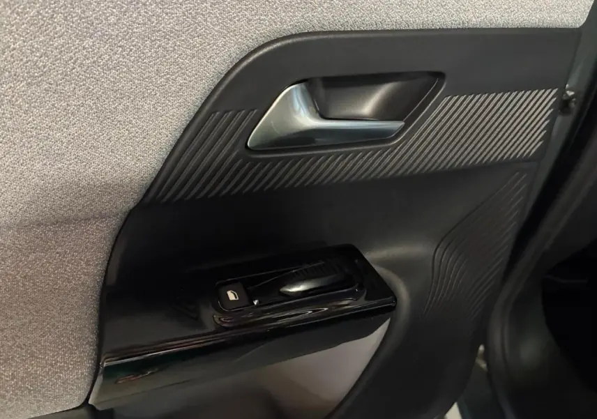 Détail de la porte côté gauche intérieure du Citroën C5 Aircross 2026, avec poignée argentée et commande de vitre noire.
