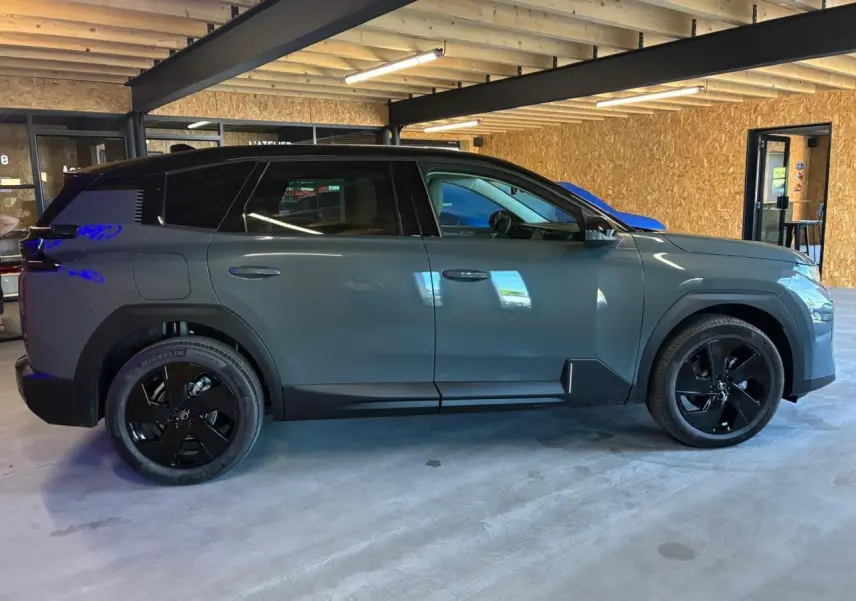 Vue de profil côté gauche du Citroën C5 Aircross 2026 vert avec toit noir et jantes noires en intérieur.
