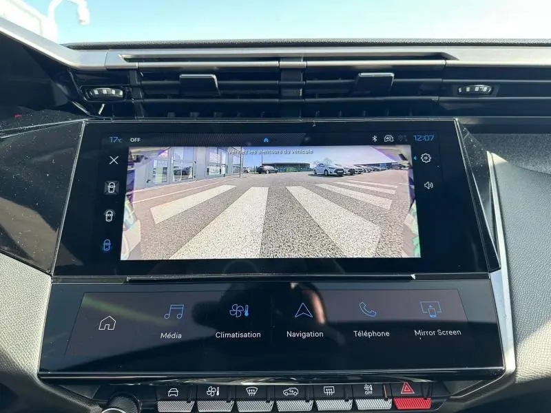 Vue rapprochée de l'écran tactile central affichant la caméra de recul dans l'habitacle d'une Peugeot 308 bleu.