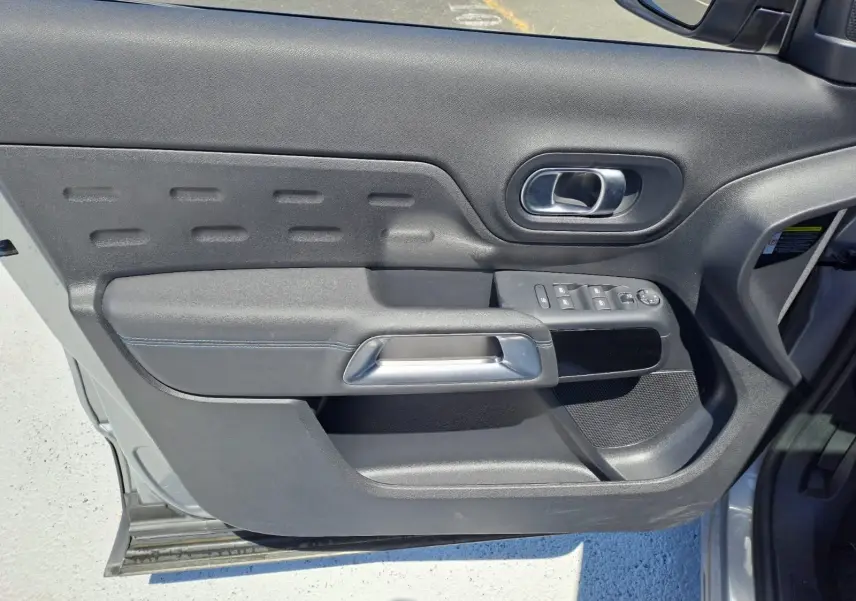 Vue intérieure de la porte avant gauche du Citroën C5 Aircross gris, avec commandes de vitres et poignée argentée.