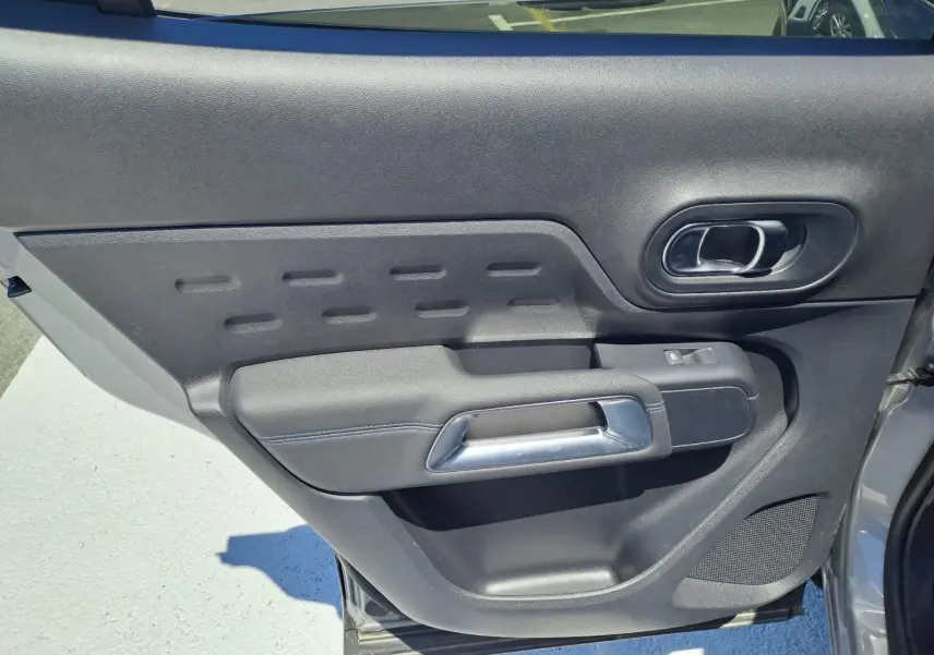 Détail de la porte arrière gauche noire du Citroën C5 Aircross 2024, avec poignée argentée et bouton de fenêtre.