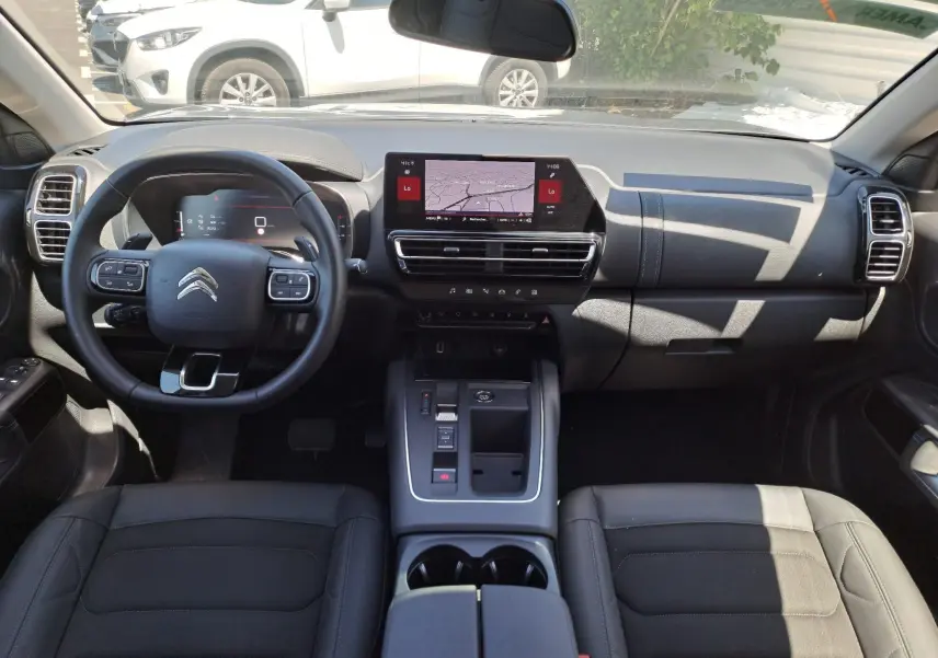 Vue intérieure avant du Citroën C5 Aircross Hybrid 2024, tableau de bord noir avec écran tactile et volant multifonction.
