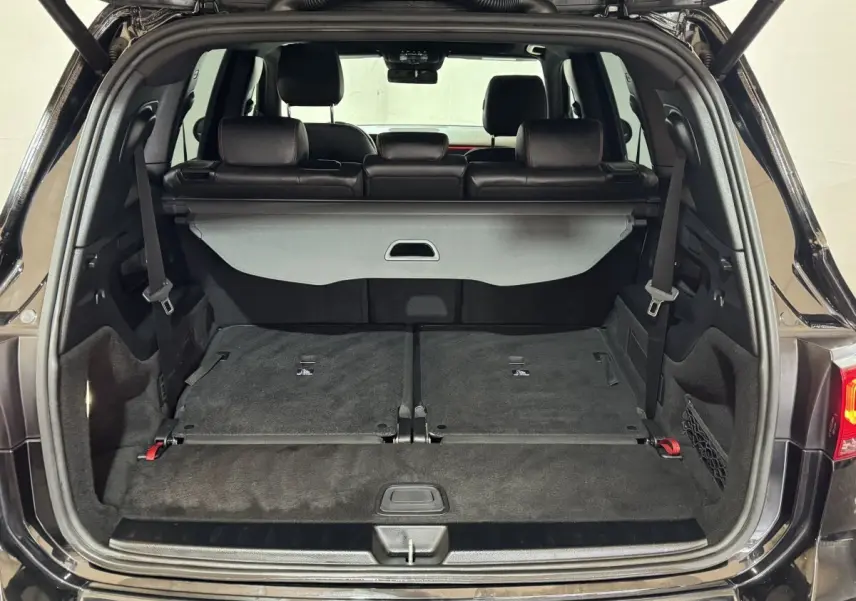 Coffre ouvert d’un Mercedes GLB 200 d AMG Line noir, montrant la 3ème rangée de sièges rabattue et l’intérieur noir.