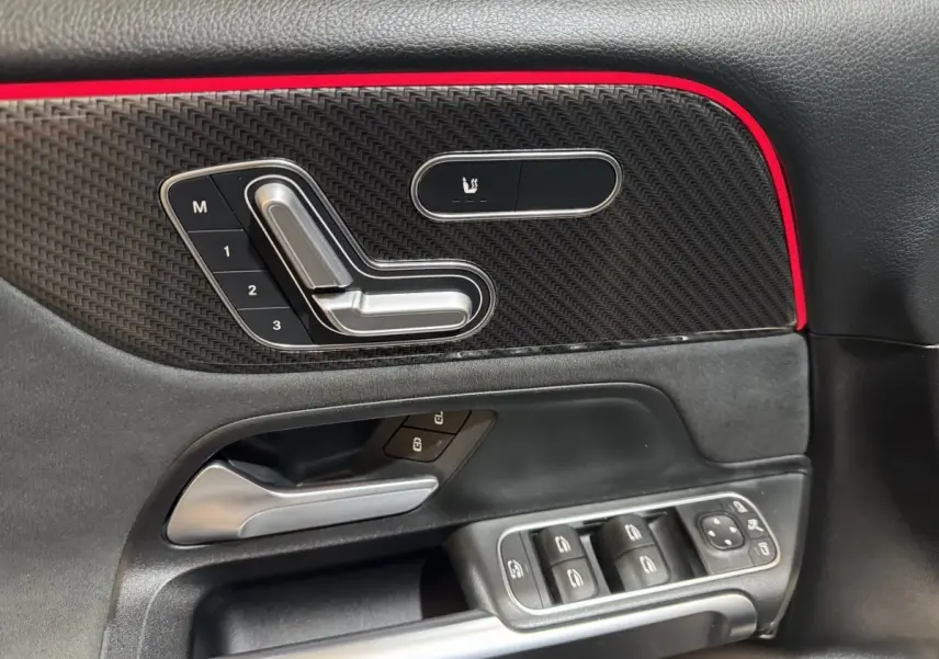 Détail de la porte côté gauche de la Mercedes GLB 200 d AMG Line noire, avec commandes sièges et boutons vitres.