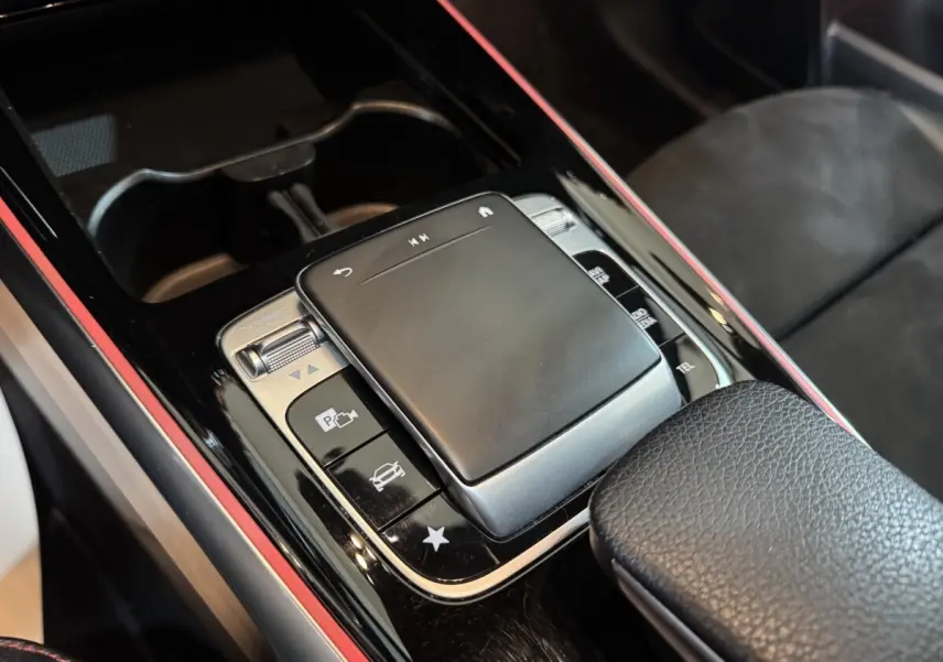 Gros plan sur la console centrale noire du Mercedes GLB 200 d AMG Line, mettant en valeur le pavé tactile et les boutons de contrôle.