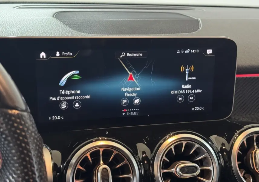 Vue rapprochée de l'écran tactile central du tableau de bord noir du Mercedes GLB 200 d AMG Line affichant navigation et radio.